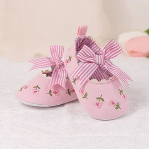 Detailed close-up of baby girl shoes with pink floral embroidery and striped bow detail