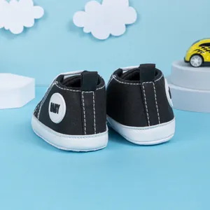 Détail de chaussures hautes en toile pour bébé en noir avec coutures blanches