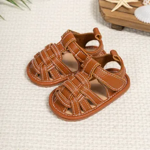 Detailed close-up of brown textured leather baby sandals with woven design and white stitching