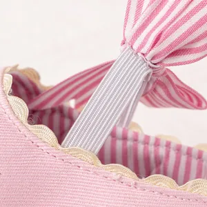 Macro detail of baby princess shoe featuring pink striped bow and soft fabric texture