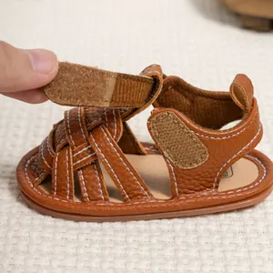 Detail of brown leather baby sandal showing the adjustable velcro strap and white stitching