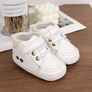Detail of white PU leather baby sneakers with velcro strap on a rustic wood background