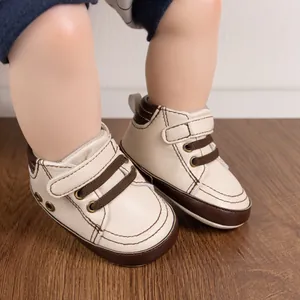 Detailed close-up of cream baby walker shoes with brown velcro strap on wooden floor