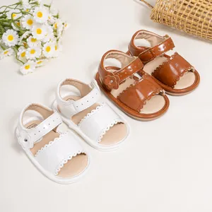 Detail of leather baby sandals featuring floral accents and wavy edge cutouts
