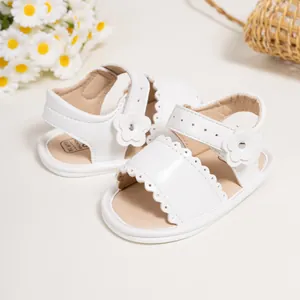 Detail of white baby flower sandals featuring scalloped edges and velcro strap closure