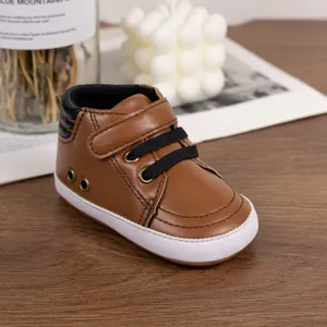 Close-up of brown faux leather baby sneakers with velcro straps on a wooden table