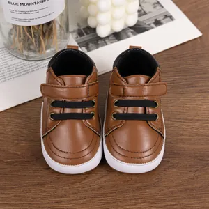 Close-up of brown leather baby walking shoes with velcro strap on a wooden surface