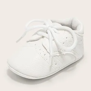 Detailed close-up of white soft leather baby walker shoes with Brogue pattern and round laces