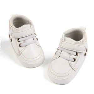Close-up of white baby sneaker with hook-and-loop strap and soft sole design