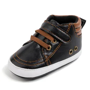 Detail view of baby walking shoes with black faux leather and soft white flexible soles