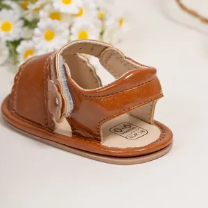Close-up of brown baby sandal featuring 3D floral applique and hook-and-loop closure