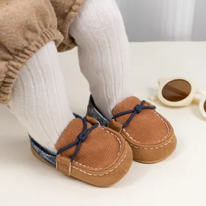 Detail von braunen Baby-Mokassins mit blauer Schleife und Patchwork-Design aus Denim
