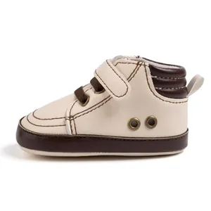 Detail of baby walking shoes showing cream faux leather and brown rubber sole textures