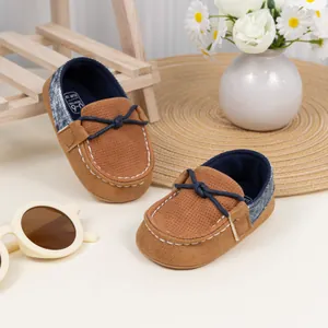 Detail von Baby-Mokassins aus braunem Wildleder mit blauen Denim-Akzenten an der Ferse