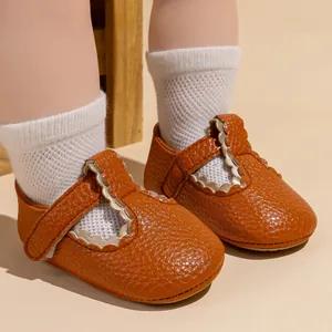 Detail van baby prinsessenschoenen in karamel generfd leer met geschulpte randen