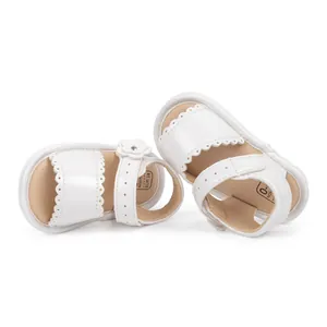 Detail of white baby sandals with floral accents and Velcro strap for 0-6 months