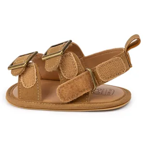 Detail view of brown fabric baby sandals with brass buckles and Velcro straps for 0-6 months