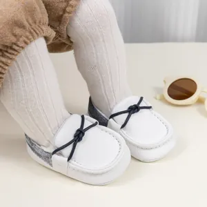 Detailansicht der weißen Baby-Loafer aus Leder mit atmungsaktiven Löchern und blauer Schleife