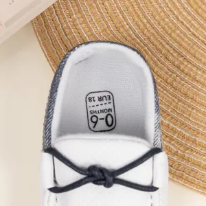 Nahaufnahme der weißen Baby-Lauflernschuhe mit atmungsaktiven Löchern und blauen Bändern