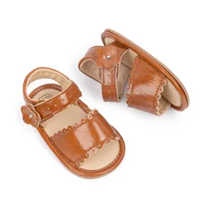 Close-up of brown baby sandals featuring scalloped edges and a decorative 3D flower detail