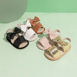Flat lay of baby PU leather sandals with bow decoration in five colors on green background