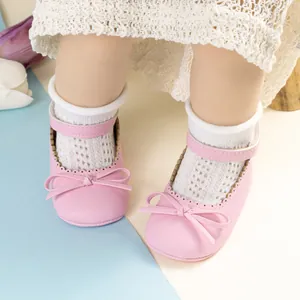 Détail de chaussures bébé Mary Jane roses avec nœud et cuir texturé sur chaussettes