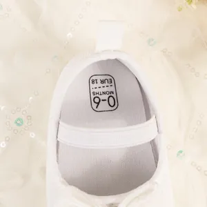 Détail de la chaussure bébé en velours blanc montrant la taille 0-6 mois et le tissu