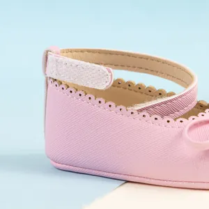 Détail de chaussures bébé roses avec bords festonnés et cuir texturé à fermeture velcro
