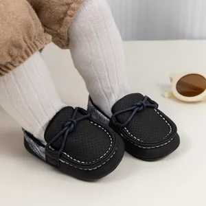 Detail von schwarzen Kleinkind-Loafers mit gelochtem Leder, Handnaht und Knoten-Akzent