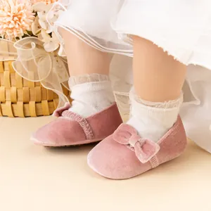 Détails des chaussures de bébé en velours rose avec nœud et chaussettes en dentelle