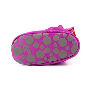 Vue détaillée des chaussures bébé en soie magenta avec points antidérapants gris sur la semelle