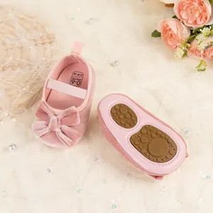 Vue détaillée des chaussons bébé en velours rose avec nœud et marquage de taille