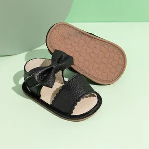 Detailed macro view of black PU leather baby sandal with bow and non-slip rubber sole