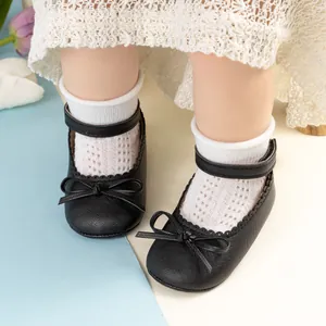 Gros plan de chaussures bébé princesse noires avec nœud et bords festonnés sur modèle