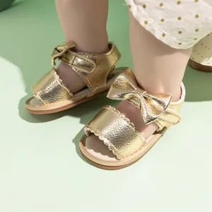 Detail of golden baby sandals with bow decoration and hook-and-loop closure for girls