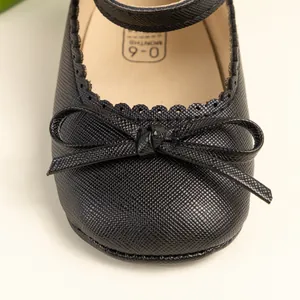Gros plan sur chaussures Mary Jane noires pour bébé avec nœud et bordure festonnée