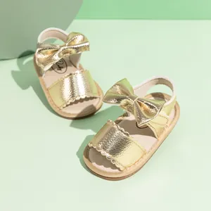 Detail of baby girl gold PU sandals featuring large bow decoration and velcro strap