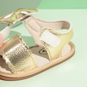 Detail of baby girl gold sandals featuring a cute bow decoration and velcro closure