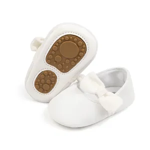 Détail de chaussures bébé en velours blanc avec nœud et semelle antidérapante à picots