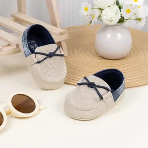 Detail von beigen Baby-Mokassins mit weichen rutschfesten Sohlen und blauem Knoten