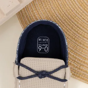 Nahaufnahme der Baby-Loafer mit beiger Ledertextur und blauer Schleifendetails