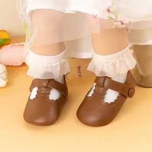 Detail of dark brown baby Mary Jane shoes with wavy cutout edges and buckle strap