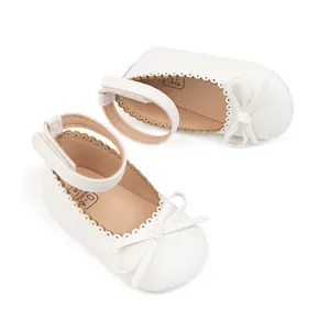 Détail de chaussures bébé blanches avec nœud, bords festonnés au laser et scratch