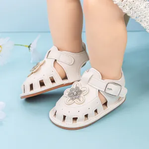 Close-up of white baby sandals featuring a decorative flower and soft cutout design