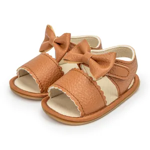 Brown faux leather baby sandals featuring a decorative bow and convenient velcro strap
