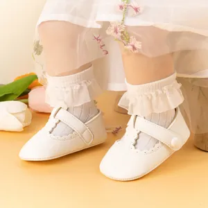 Close-up of white baby Mary Jane shoes with scalloped edges and lace socks set