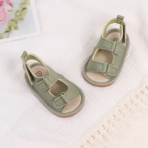 Top view of sage green baby sandals with double hook and loop straps on white rug