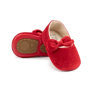 Détail de chaussures bébé en velours rouge avec nœud et semelle antidérapante