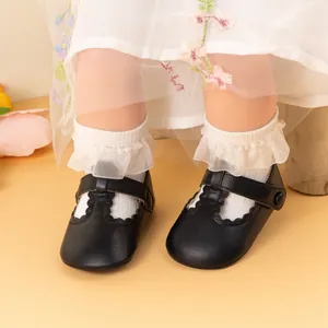 Detail of baby Mary Jane shoes with scalloped cutouts and lace socks on floral background