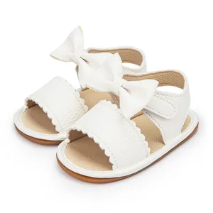 Close-up of white baby girl sandals featuring decorative bow and PU leather texture